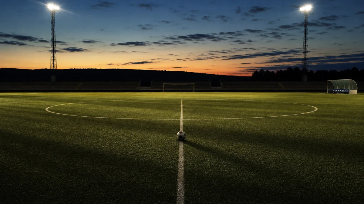Fotboll på mittlinjen på en tom plan i skymningsljus
